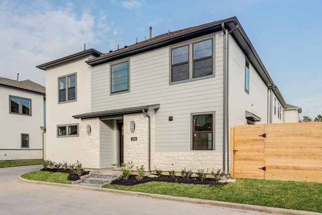 view of front of house featuring stone siding and fence