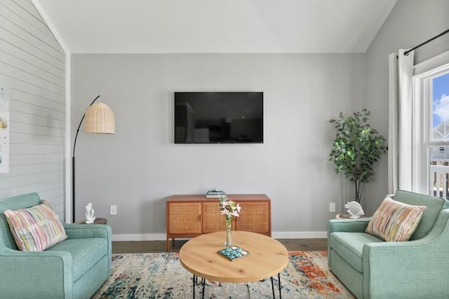 living area featuring lofted ceiling, wood finished floors, and baseboards