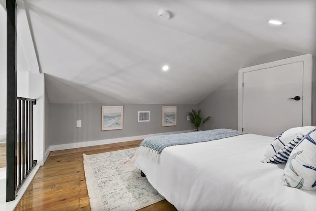 bedroom featuring baseboards, visible vents, lofted ceiling, wood finished floors, and recessed lighting