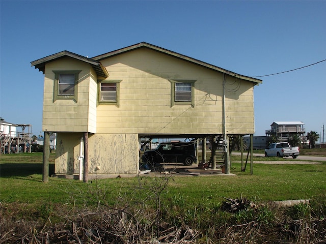 rear view of property featuring a carport, stairway, and a lawn