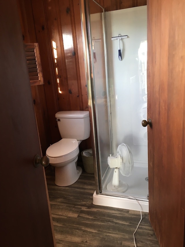 full bathroom with toilet, a stall shower, and wood finished floors