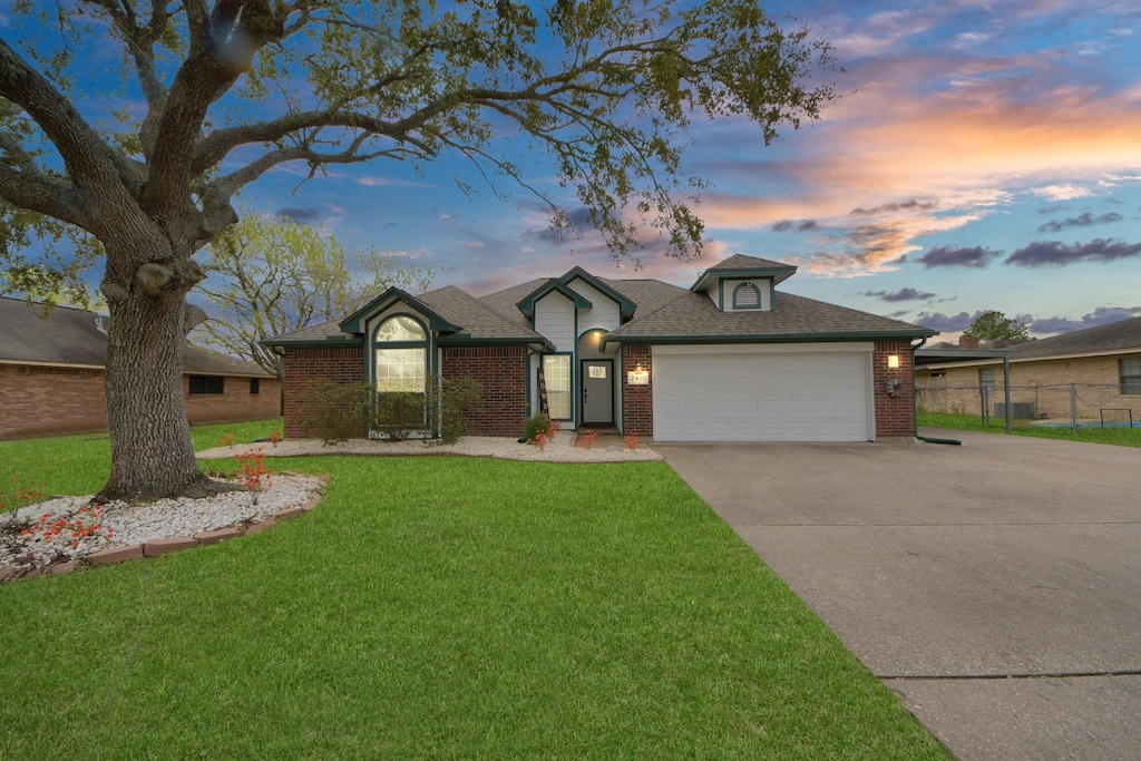 single story home with a garage, a front yard, brick siding, and driveway