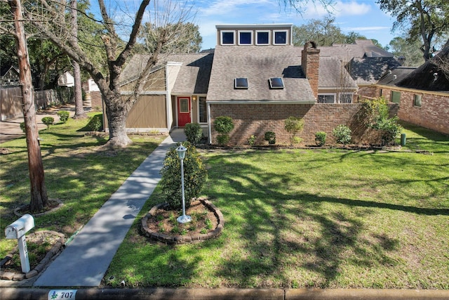 view of front of property featuring fence, a front yard, a shingled roof, brick siding, and a chimney