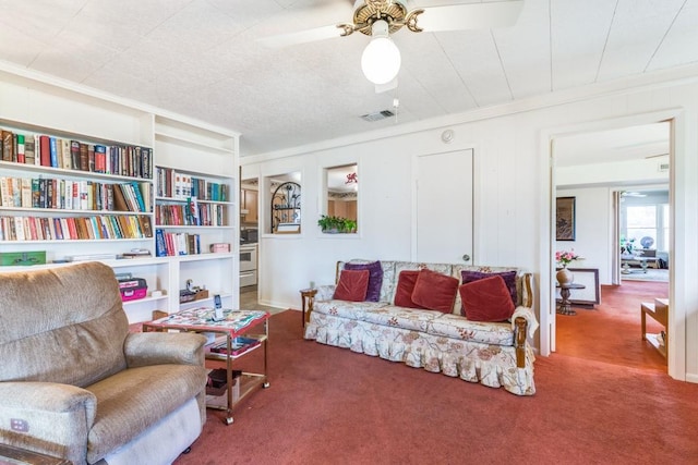 sitting room featuring visible vents, a ceiling fan, ornamental molding, carpet floors, and built in shelves