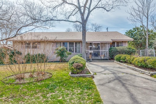 single story home with a porch, brick siding, fence, driveway, and a front yard