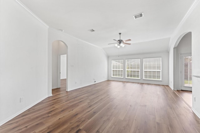 empty room with ornamental molding, visible vents, ceiling fan, and wood finished floors