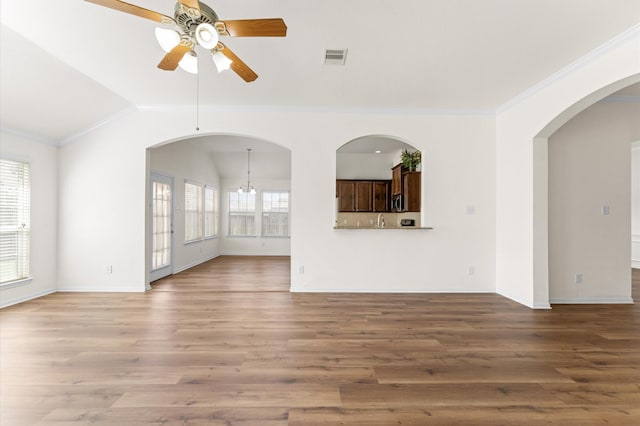 unfurnished living room with visible vents, wood finished floors, vaulted ceiling, crown molding, and ceiling fan with notable chandelier