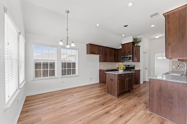 kitchen with a sink, visible vents, vaulted ceiling, stainless steel microwave, and an inviting chandelier