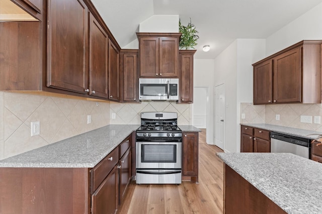 kitchen with appliances with stainless steel finishes, light wood-type flooring, backsplash, and light stone countertops