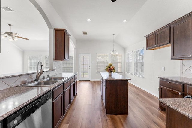 kitchen with stainless steel dishwasher, a sink, visible vents, and decorative backsplash