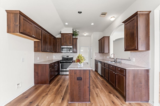 kitchen featuring visible vents, appliances with stainless steel finishes, wood finished floors, a center island, and a sink