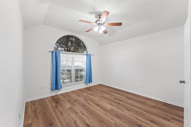 empty room with lofted ceiling, wood finished floors, a ceiling fan, and baseboards