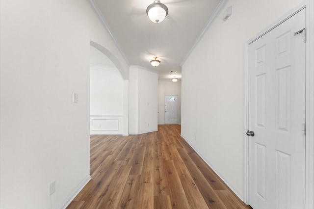 hall with arched walkways, wood finished floors, and crown molding