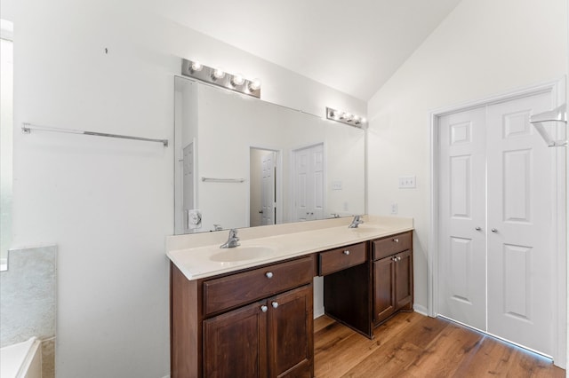 bathroom with double vanity, vaulted ceiling, a sink, and wood finished floors