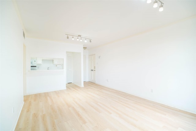 spare room featuring track lighting, crown molding, and light wood finished floors