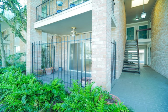 exterior space with brick siding, fence, and ceiling fan