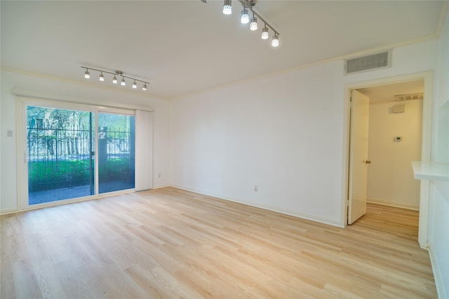 empty room featuring ornamental molding, light wood-style flooring, visible vents, and track lighting