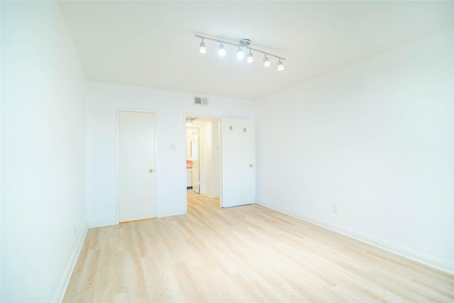 empty room featuring light wood-style floors, visible vents, and baseboards