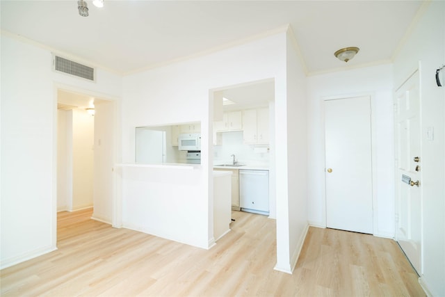 kitchen featuring white appliances, a sink, visible vents, white cabinets, and light wood finished floors