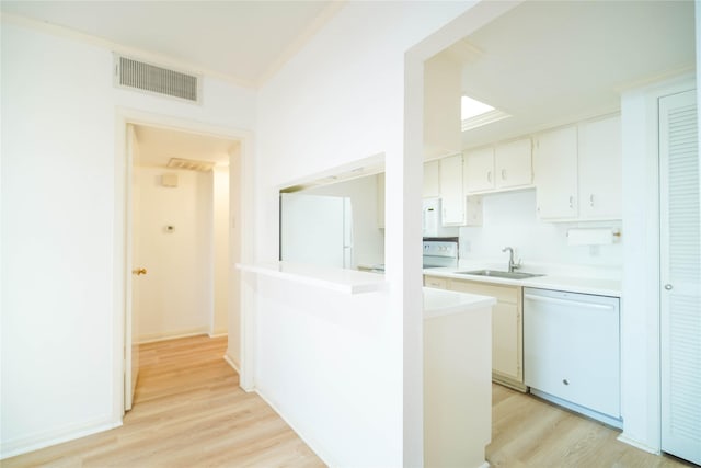 kitchen with light countertops, visible vents, light wood-style flooring, a sink, and white appliances