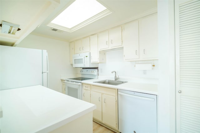 kitchen with white appliances, a sink, visible vents, white cabinetry, and light countertops