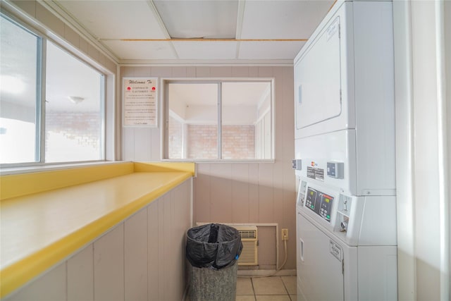 shared laundry area featuring light tile patterned floors, stacked washer / dryer, and a wall mounted air conditioner