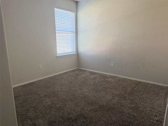 spare room featuring carpet floors and baseboards