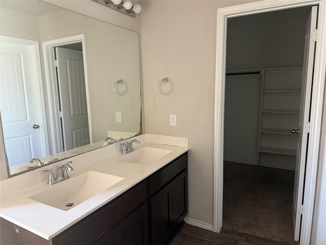 full bath with a sink, a spacious closet, baseboards, and double vanity