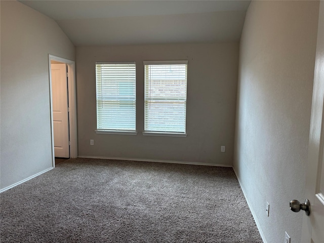 empty room featuring lofted ceiling, carpet floors, and baseboards