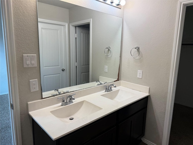 bathroom with double vanity, a sink, and a textured wall