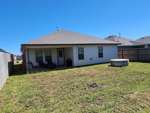 back of property featuring a fenced backyard, a shingled roof, a lawn, and a patio