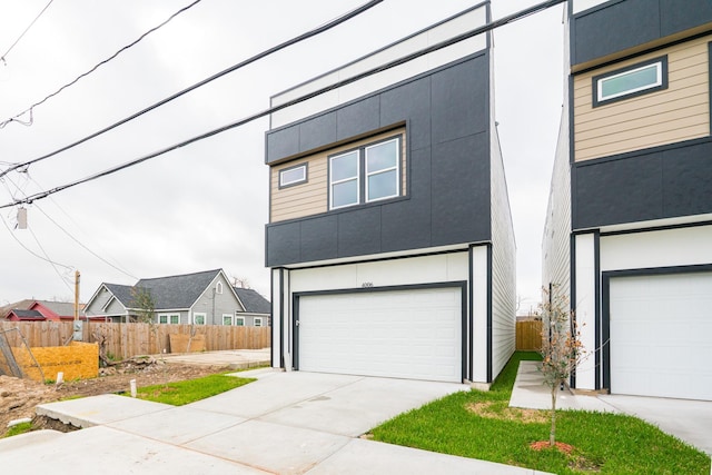 modern home with fence, driveway, an attached garage, and stucco siding