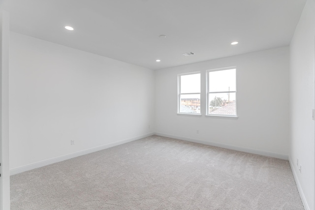 spare room featuring baseboards, recessed lighting, visible vents, and light colored carpet