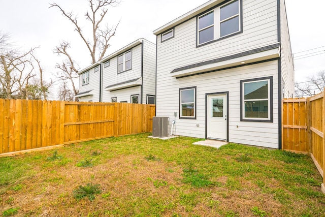 rear view of house with central AC, a yard, and a fenced backyard