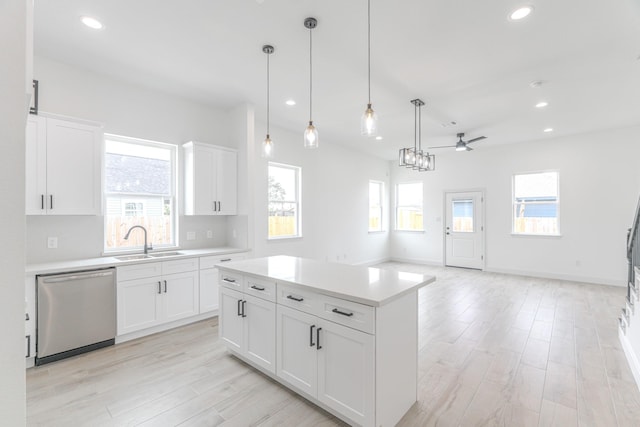 kitchen featuring light countertops, stainless steel dishwasher, plenty of natural light, and a sink