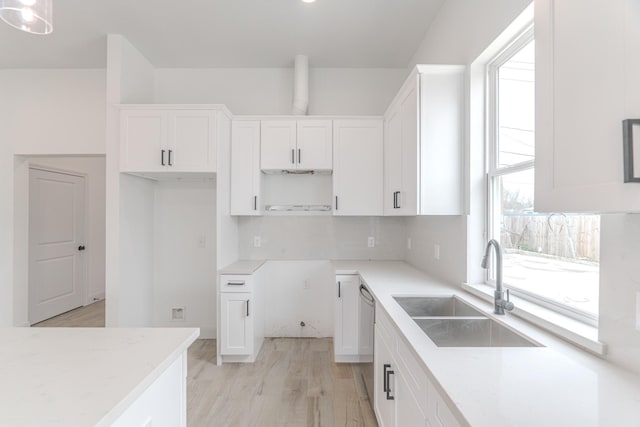 kitchen with backsplash, white cabinetry, a sink, and light wood-style flooring