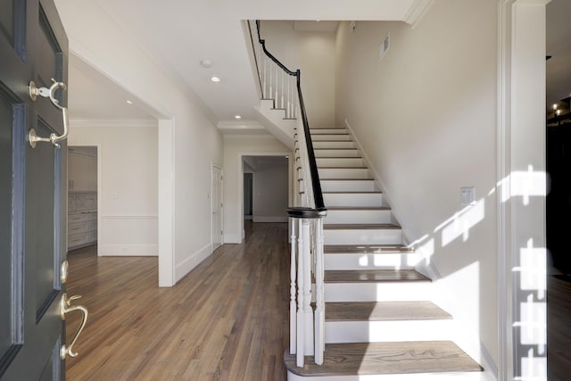 entryway with crown molding, visible vents, stairway, wood finished floors, and baseboards