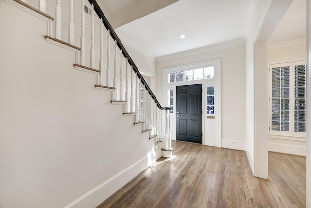 foyer entrance with baseboards, wood finished floors, and crown molding