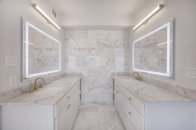 bathroom with marble finish floor, two vanities, a sink, and visible vents