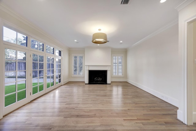 unfurnished living room with visible vents, baseboards, a fireplace with flush hearth, ornamental molding, and light wood-style floors