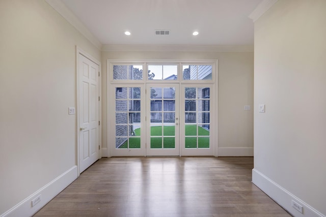 spare room featuring a wealth of natural light, visible vents, crown molding, and wood finished floors