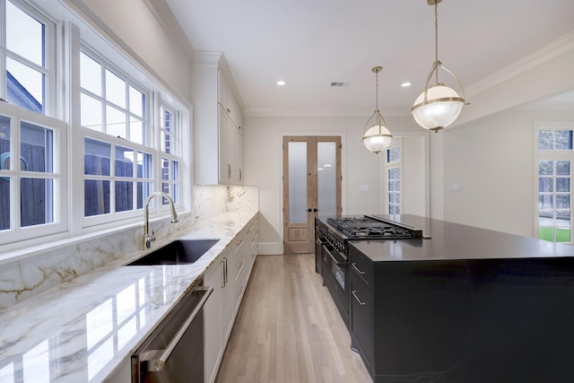 kitchen featuring crown molding, visible vents, a sink, dark cabinets, and dishwasher