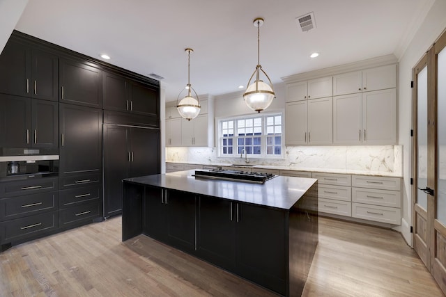 kitchen with tasteful backsplash, light wood-style floors, visible vents, and a kitchen island