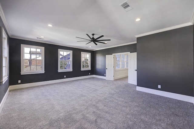 carpeted spare room with ornamental molding, a ceiling fan, visible vents, and baseboards