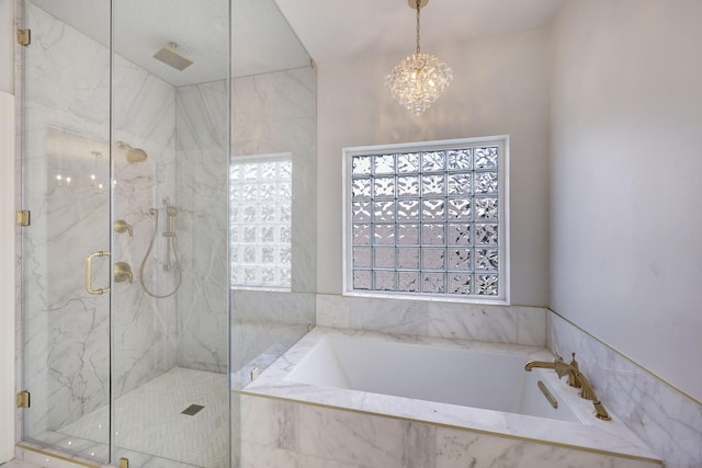 full bathroom featuring a garden tub, a notable chandelier, and a marble finish shower