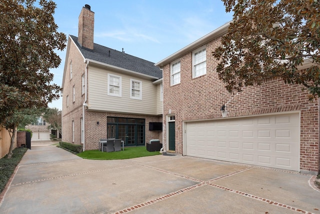 view of front facade featuring brick siding, a chimney, central AC, a garage, and driveway