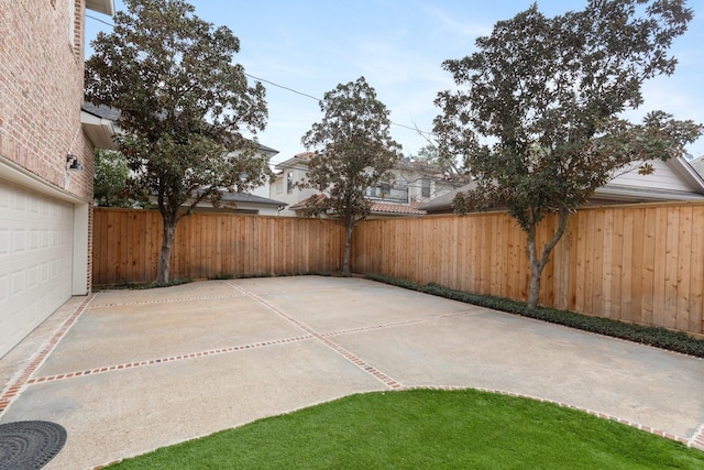 view of patio featuring a garage, fence, and driveway