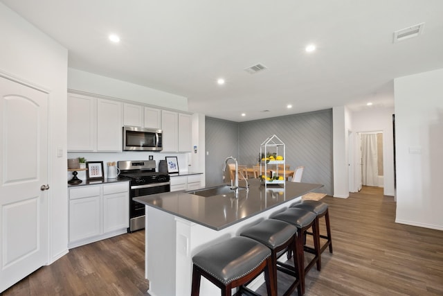 kitchen featuring dark countertops, dark wood-style floors, appliances with stainless steel finishes, and a sink