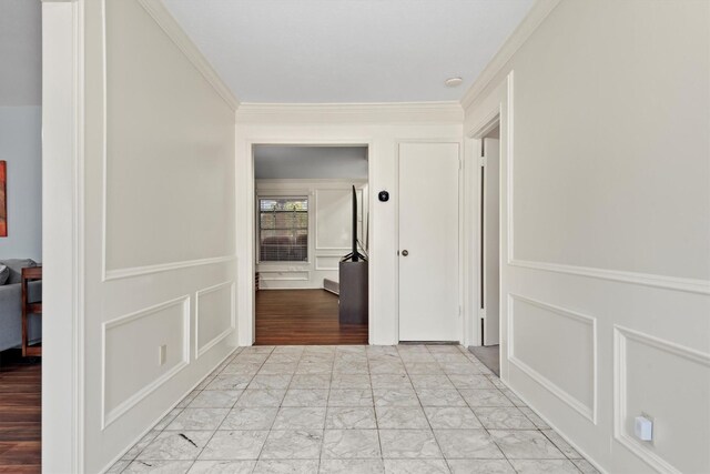 hallway featuring marble finish floor, a decorative wall, and crown molding