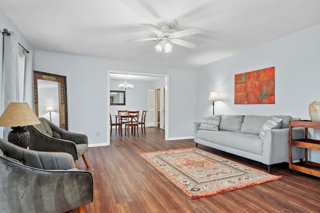 living room with ceiling fan with notable chandelier, baseboards, and wood finished floors